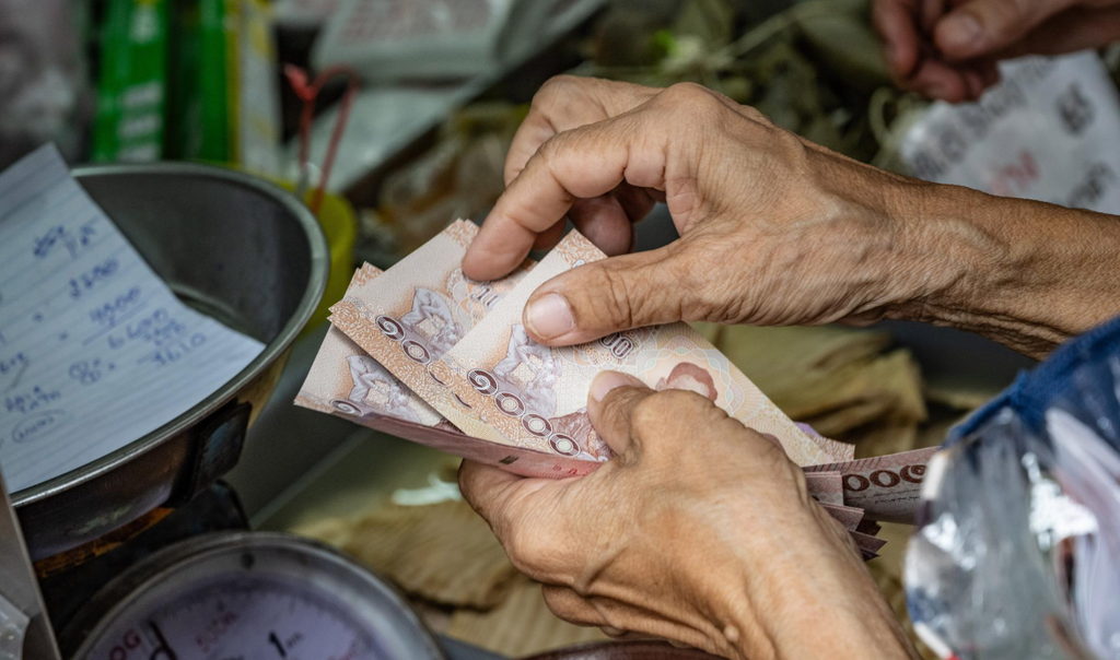Oplichting tijdens backpacken: toerist controleert buitenlands geld op een markt.